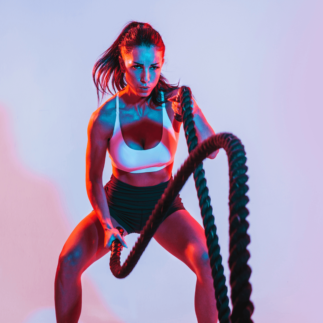 Woman performing battle rope exercise in gym