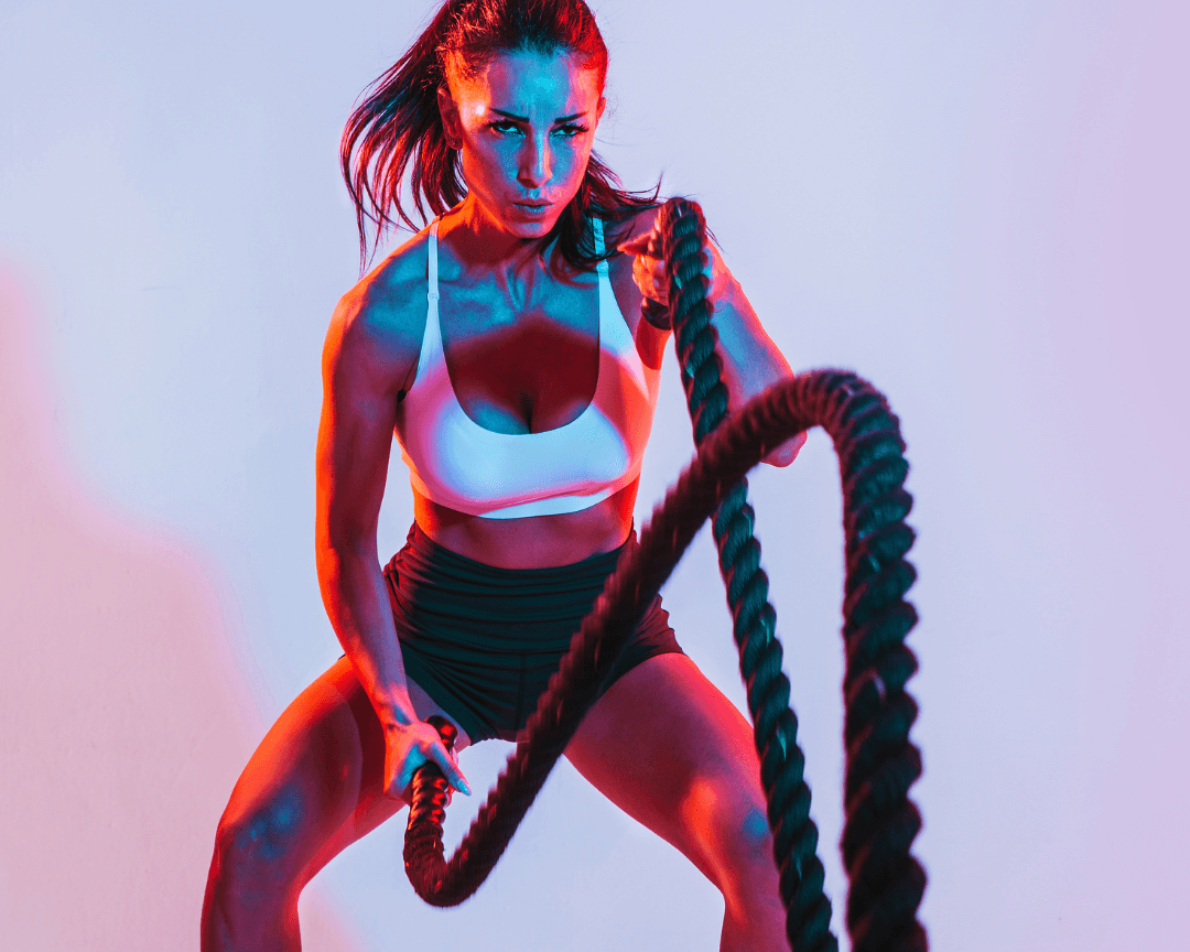 Woman performing battle rope exercise in gym